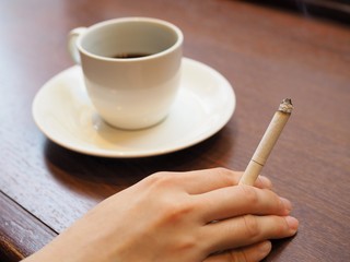 煙草を吸う女性の手とコーヒー