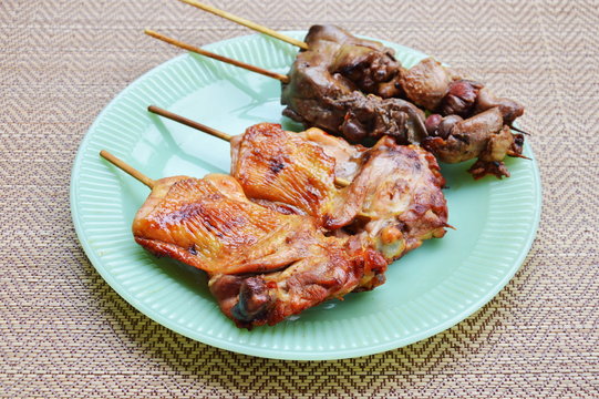 roasted chicken and entrails in wooden stick on dish