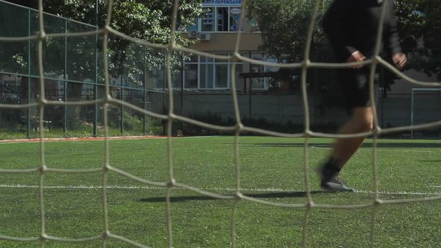 Man playing football and the ball hit the goal