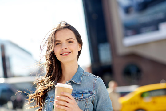 happy young woman drinking coffee on city street