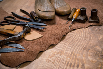 Set of leather craft tools on wooden background. Workplace for shoemaker.