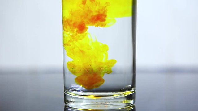 Drop yellow ink in to water in glass. slow motion