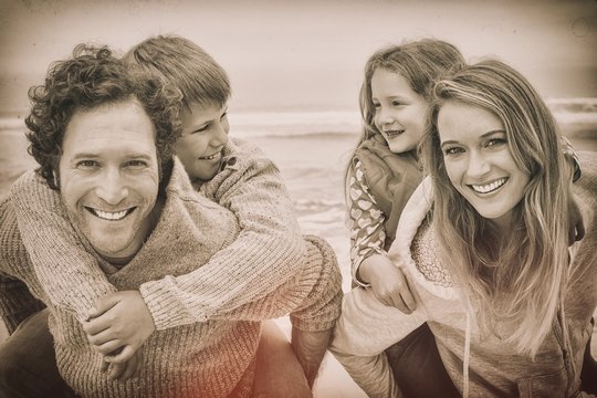 Happy Couple Piggybacking Kids At Beach