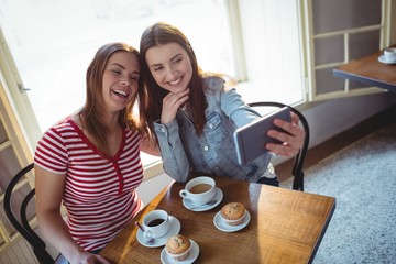 High angle view of happy friends taking selfie at cafe