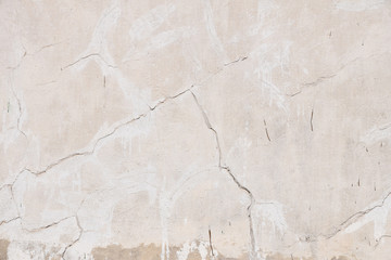 Old beige pink painted plaster wall with cracks