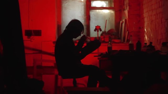 Silhouette artist paints a mask in a dark studio with a red light
