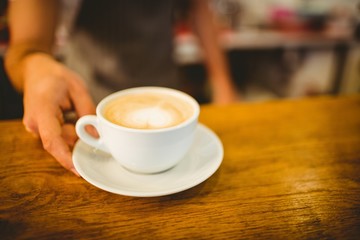 Midsection of barista serving heart shape frothy coffee at cafe