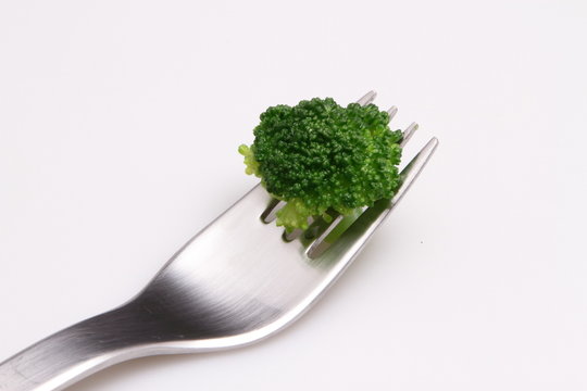 boild broccoli with salada fork on white background