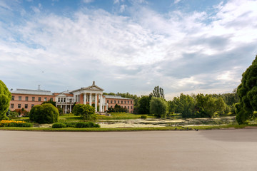 Obraz premium The building is of pink brick with white columns on the shore of the pond. The main Botanical garden. Moscow. 