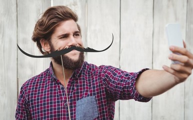 Composite image of hipster taking selfie against wooden wall