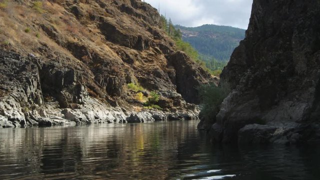 Looking back at a large rock in the channel of the Rogue River Canyon; raft appears