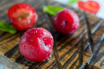 fresh juicy plums with drops on a brown background