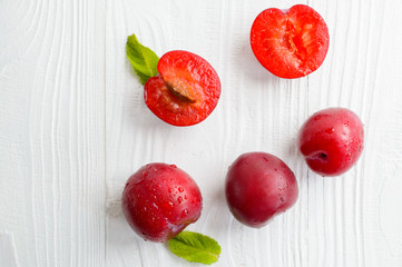 fresh juicy plums with drops on a white background, top view