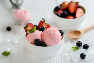 Strawberry ice cream with berry in white bowl on wooden table