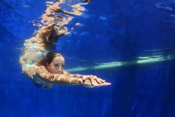 Beautiful young woman dive underwater with fun from poolside to blue pool. Healthy active lifestyle, people water sport activity to keep fit and swimming lessons in health club on summer holidays.