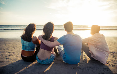 Four friends enjoying the sunset at the beach