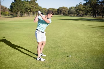 Full length of young golfer taking shot