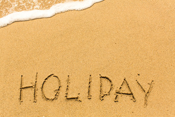 Holiday - drawn by hand on a sandy golden sea beach.