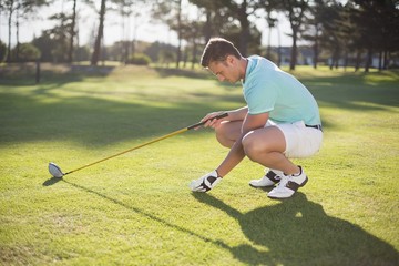 Obraz premium Side view of young man placing golf ball on tee 