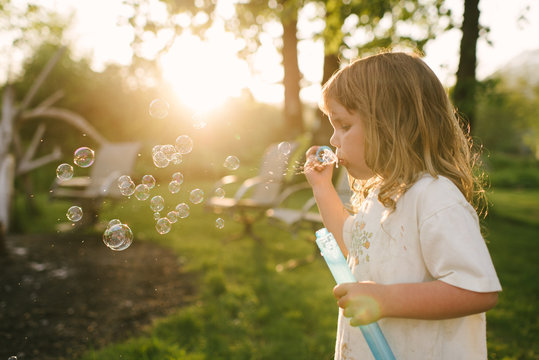 Young girl blowing bubbles with bubble wand