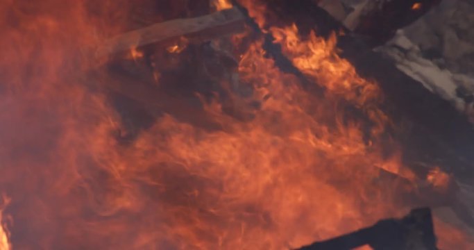 Flames rise above a pile of timbers reduced to rubble in a house fire
