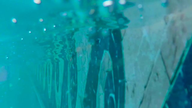 Close up of the side of a pool as the water level goes above and below the camera. Slow motion, 240fps