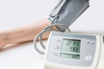 Patient suffers from hypertension. Woman is measuring blood pressure with digital monitor.