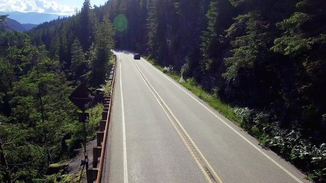 Aerial Two Cars Driving Down Sunny Forest Wilderness Mountain Road Opposite Directions