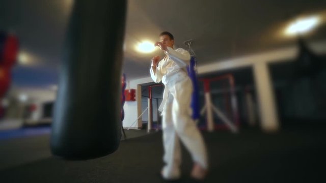 Taekwondo training with punching bag, backlit. Slowly