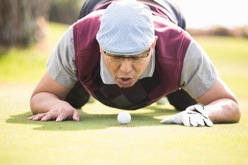 Golfer blowing ball in the hole