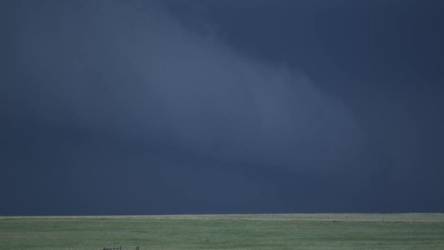 Tracking a fast-moving beavertail cloud sweeping across dark sky over prairie farmland, time lapse
