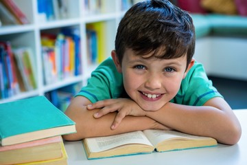 Smiling boy with book in school library