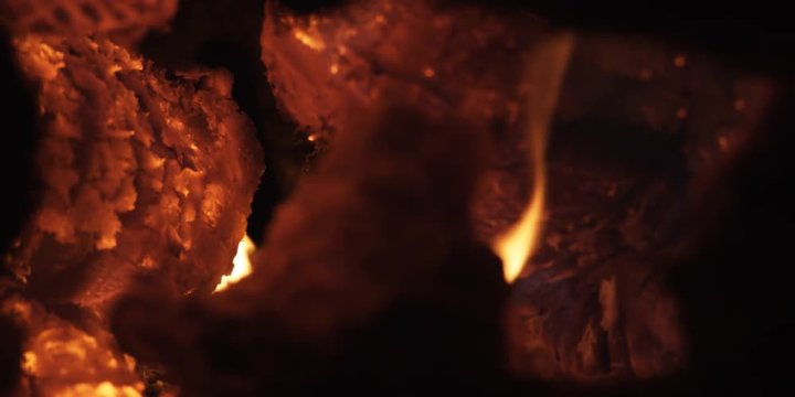 Close-up flames over a chunk of glowing wood on a fire