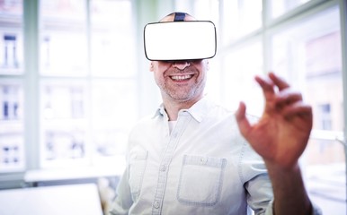 Naklejka na ściany i meble Smiling graphic designer using virtual reality headset 