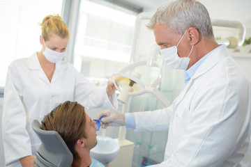 Obraz premium Dentist and assistant with male patient