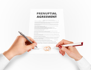 Man and woman sign prenuptial agreement near gold rings. Legal prenup document contract signing by...
