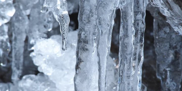 Close-up of icicles with water dripping from tip of one