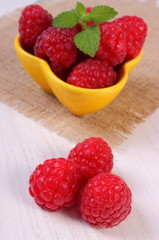Fresh raspberries and lemon balm on white wooden table, healthy food