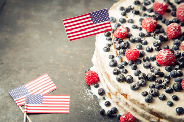 Patriotic American flag cake with blueberries and strawberries on vintage white background