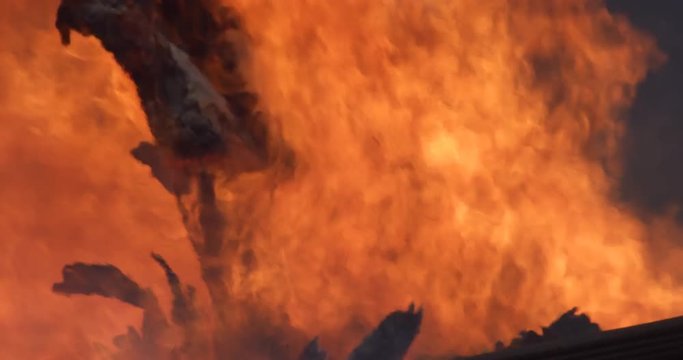 Flames devour a segment of wall in a burning house