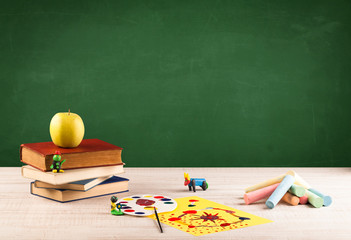 School items on desk with empty chalkboard