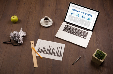 Laptop on wooden desk with office suplies