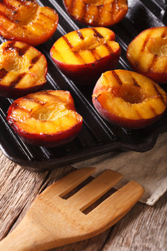 Summer dessert: Cooking Ripe peaches on a grill pan close-up. vertical
