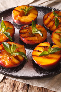 Ripe peaches grilled with powdered sugar and mint macro on a plate. Vertical
