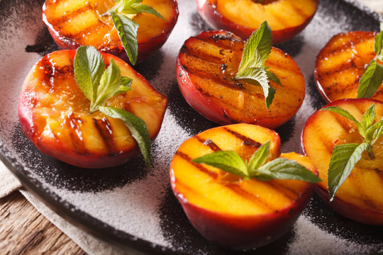 Ripe peaches grilled with powdered sugar and mint macro on a plate. horizontal
