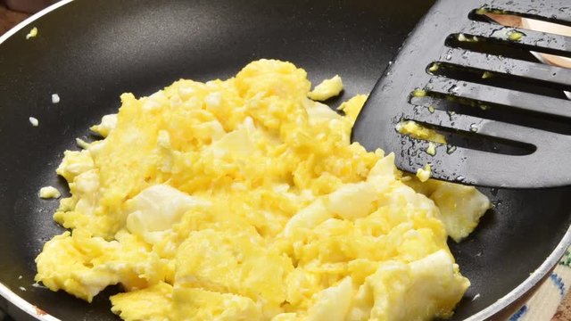Zoom out on scrambled eggs in a frying pan
