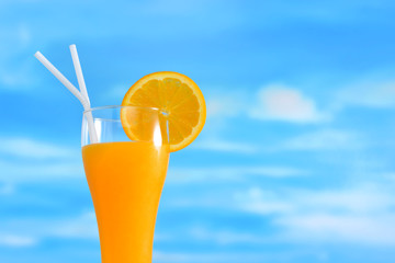 Orange juice and slices of orange on sky background