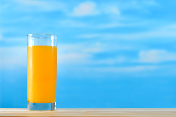 Fresh orange juice in glass on sky background