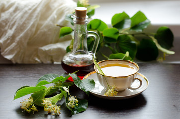 porcelain Cup of Linden tea and Maple syrup on a background of dark wood