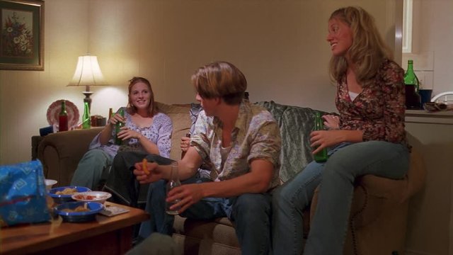 Two teenage couples sitting and drinking beer in a living room
